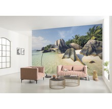 Woonkamer met foto van een tropisch strand, bank, fauteuil en salontafels