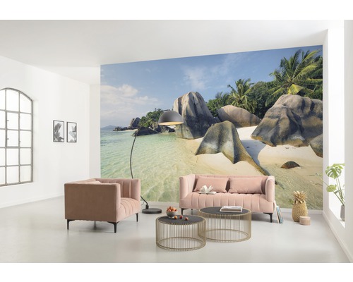 Woonkamer met foto van een tropisch strand, bank, fauteuil en salontafels