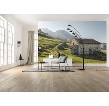 Woonkamer met fotobehang van een stenen huis in een groen heuvellandschap