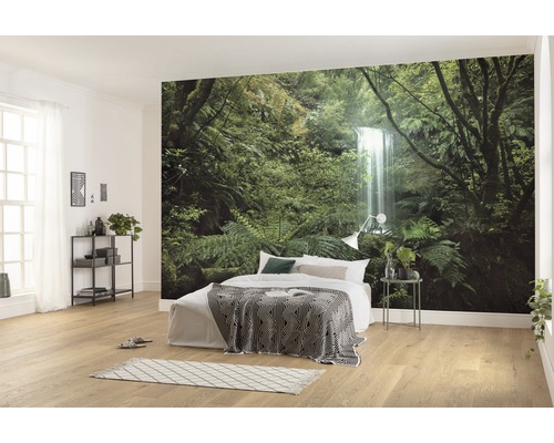 Lichte slaapkamer met fotobehang van een bos met waterval, bed met deken en nachtkastje