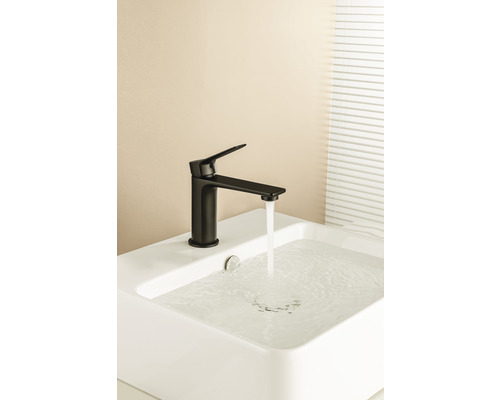 Zwarte kraan op een witte wastafel met stromend water.