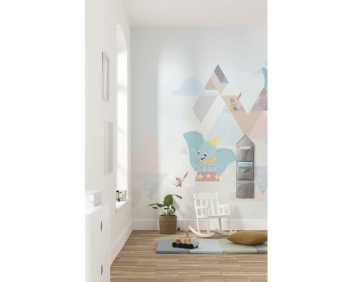 Lichte kinderkamer met Dumbo muursticker, speelmat, schommelstoel en wandrek