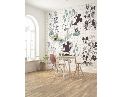 Een eetkamer met een eettafel, stoelen en een muur met Mickey Mouse motieven.