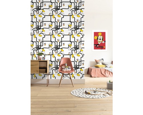 Kinderkamer met behang met Mickey Mouse patroon, bed, stoel, tafel en speelgoed