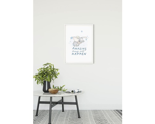 Ingelijste muurkunst met olifantmotief en de tekst ''Amazing things will happen'', geplaatst boven een tafel met decoratie