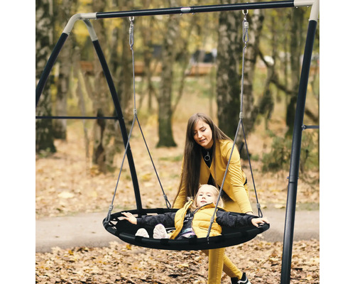 Moeder en kind op een ronde schommel in de tuin