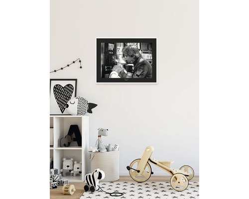 Kinderkamer met een zwart-wit foto aan de muur, een plank met speelgoed en een houten fiets