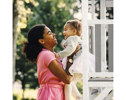 Moeder en kind spelen op een speeltoren in de tuin.