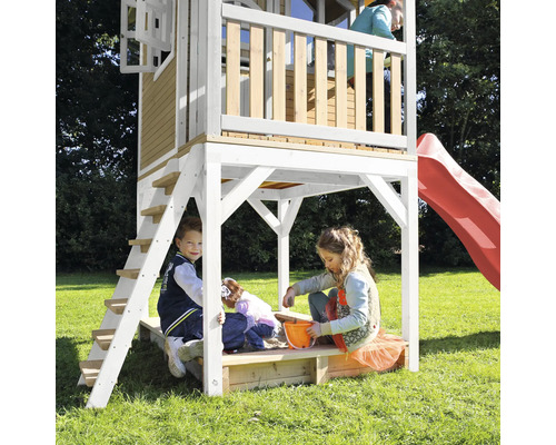 Speelhuis met glijbaan en zandbak met spelende kinderen in de tuin