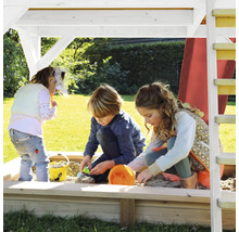 Drie kinderen spelen in de zandbak onder een speeltoren in de tuin.