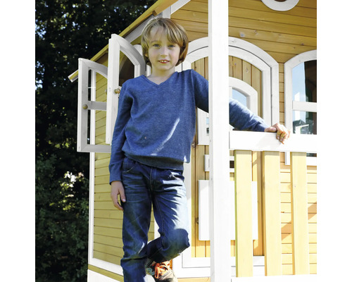 Kind staat voor een houten speelhuis met een open raam.