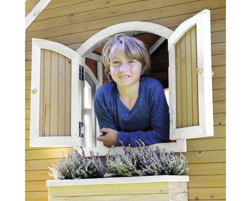 Jongen kijkt uit het raam van een houten speelhuis met vensterbank