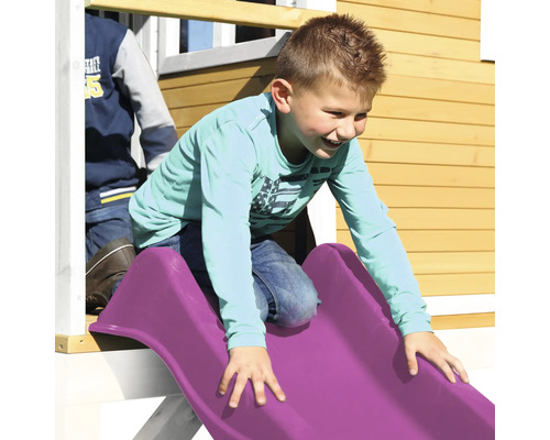 Jonge schuift op een kunststof glijbaan van een speelhuis.