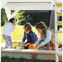 Drie kinderen spelen in een zandbak met overkapping in de tuin.