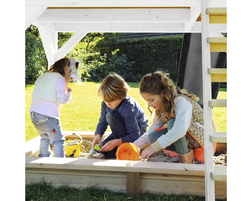 Drie kinderen spelen in een zandbak met overkapping in de tuin.