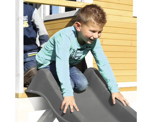 Jongen glijdt van een glijbaan op een speelhuis