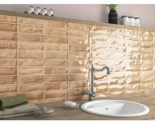 Badkamer met wastafel, kraan en wandtegels in bruine look