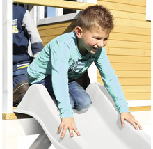 Jongen glijdt van een glijbaan van een speelhuis