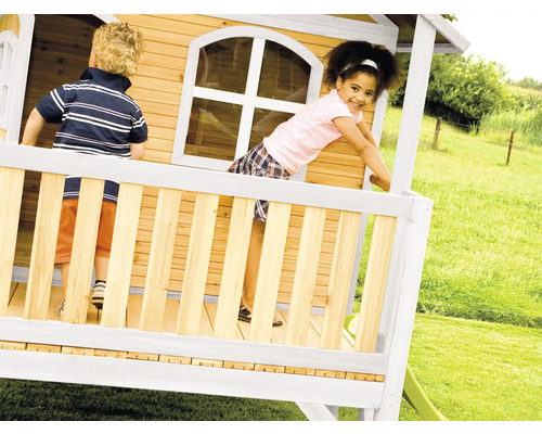 Kinderen spelen in een houten speelhuis met glijbaan in de tuin.
