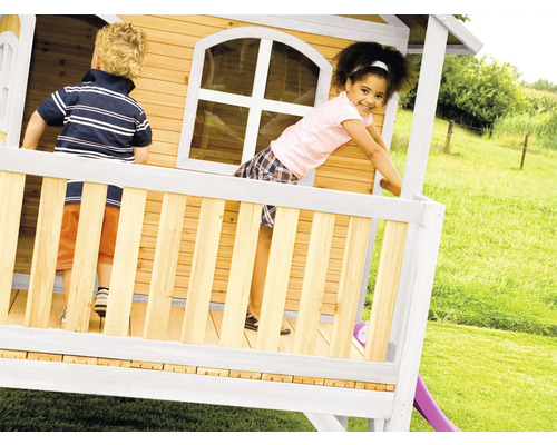 Kinderen spelen in een houten speelhuis met glijbaan in de tuin.