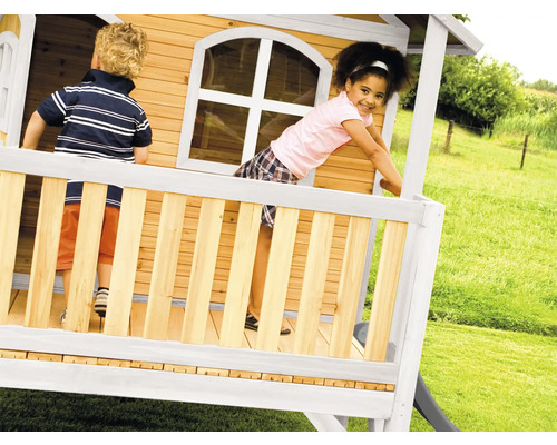 Kinderen spelen in een houten speelhuis met glijbaan in de tuin.