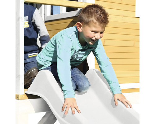 Jonge glijdt van een glijbaan van een speelhuis