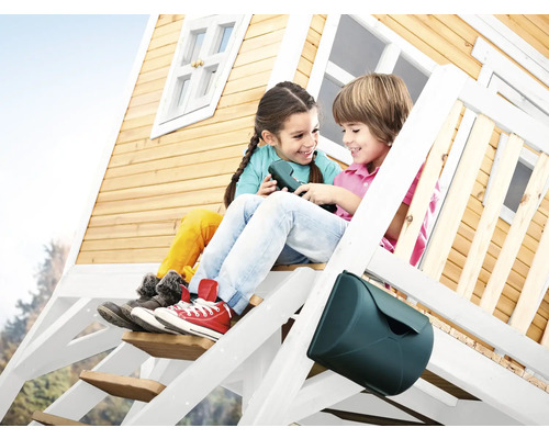 Twee kinderen zitten op de trap van een houten speelhuis met een brievenbus.