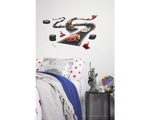 Decoratieve muursticker met Disney Cars racebaanmotief boven een kinderbed