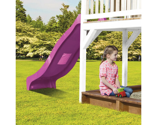 Speeltoren met glijbaan en meisje in zandbak