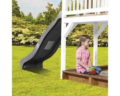 Speeltoren met glijbaan en zandbak in de tuin met spelend kind