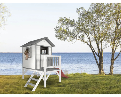 Houten speelhuis met trap en glijbaan in de tuin met uitzicht op het meer