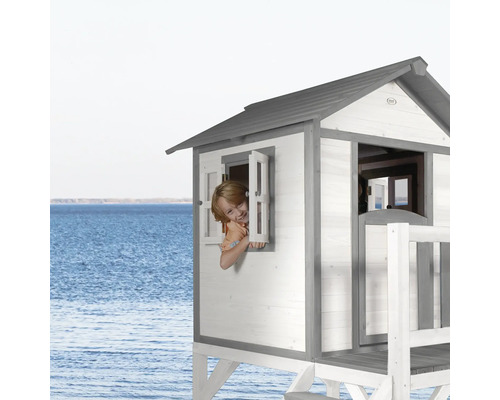 Houten speelhuis met raam en kind op de achtergrond van de zee