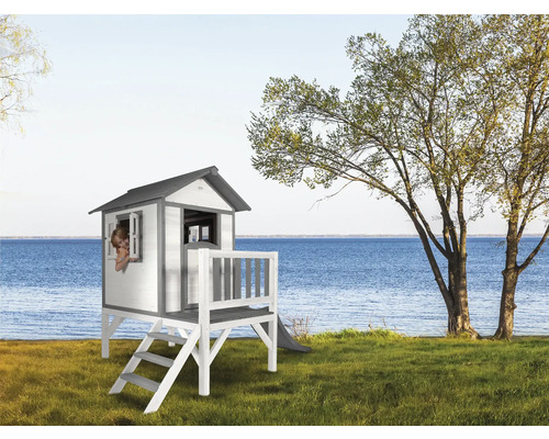 Houten speelhuis met glijbaan op een gazon aan een meer