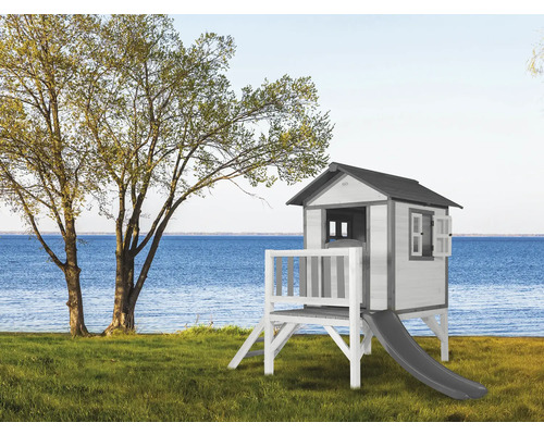 Speelhuis met glijbaan op een gazon nabij een meer