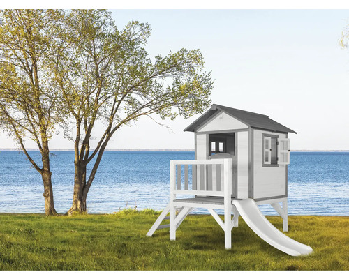 Speelhuis met glijbaan op een groen gazon met uitzicht op het water