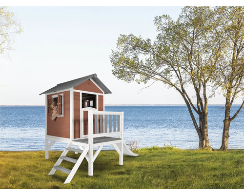 Houten speelhuis met glijbaan en terras in de tuin met uitzicht op het meer.