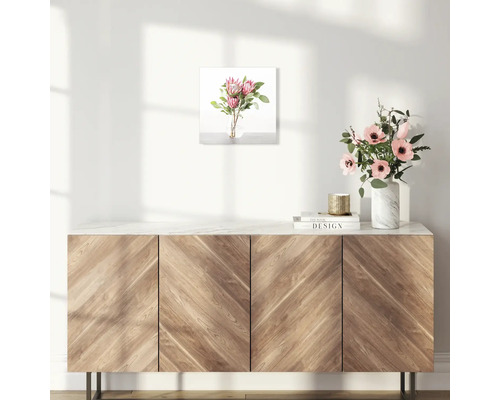 Wanddecoratie met bloemstuk boven houten kast