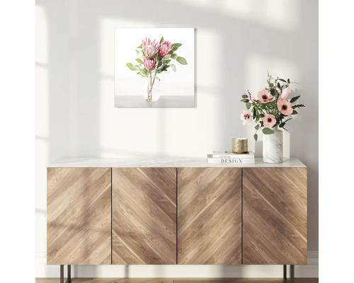 Decoratieve afbeelding met bloemstuk boven een houten kast.