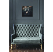 Woonkamer met bank en een foto van een hert aan de muur.