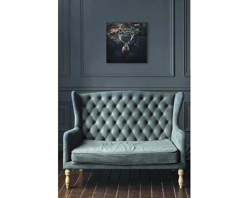 Woonkamer met bank en een foto van een hert aan de muur.