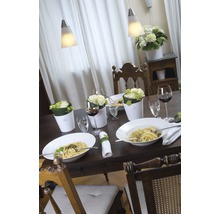 Gedekte eettafel met eten, drinken, bloemen en lampen