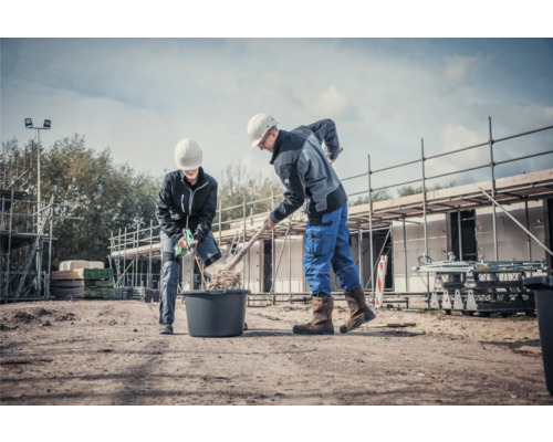 Twee bouwvakkers werken met een schop en mortelmixer op een bouwplaats.