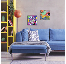 Woonkamer met blauwe bank, gele kast en schilderijen