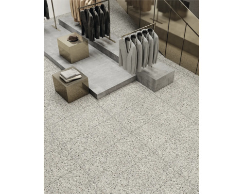 Interieurweergave met vloertegels in terrazzo-look, kledingrekken en verkoopdisplays.