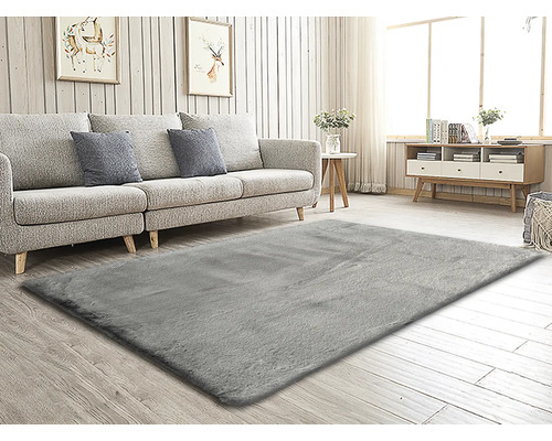 Woonkamer met grijs tapijt, bank, tafel en dressoir