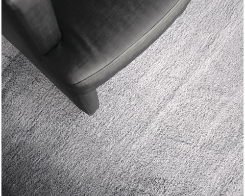 Detailopname van een lichtgekleurd tapijt naast een meubelstuk