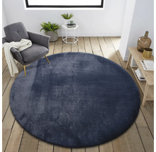 Scene met rond, textiel tapijt in een heldere kamer met een fauteuil, bijzettafel en houten plank.