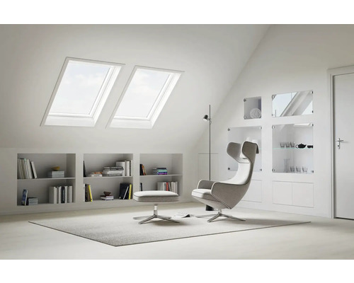 Lichte zolderkamer met dakramen, rekken en fauteuil