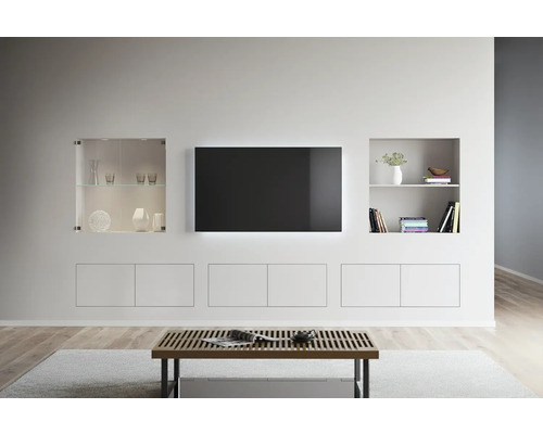 Lichte woonkamerinrichting met tv, planken en een salontafel.