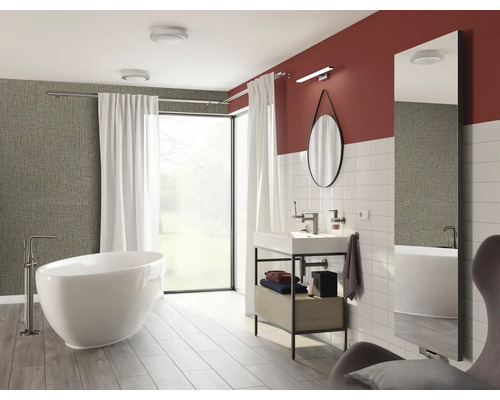 Lichte badkamer met bad, wastafel, spiegel en raam voor een moderne sfeer